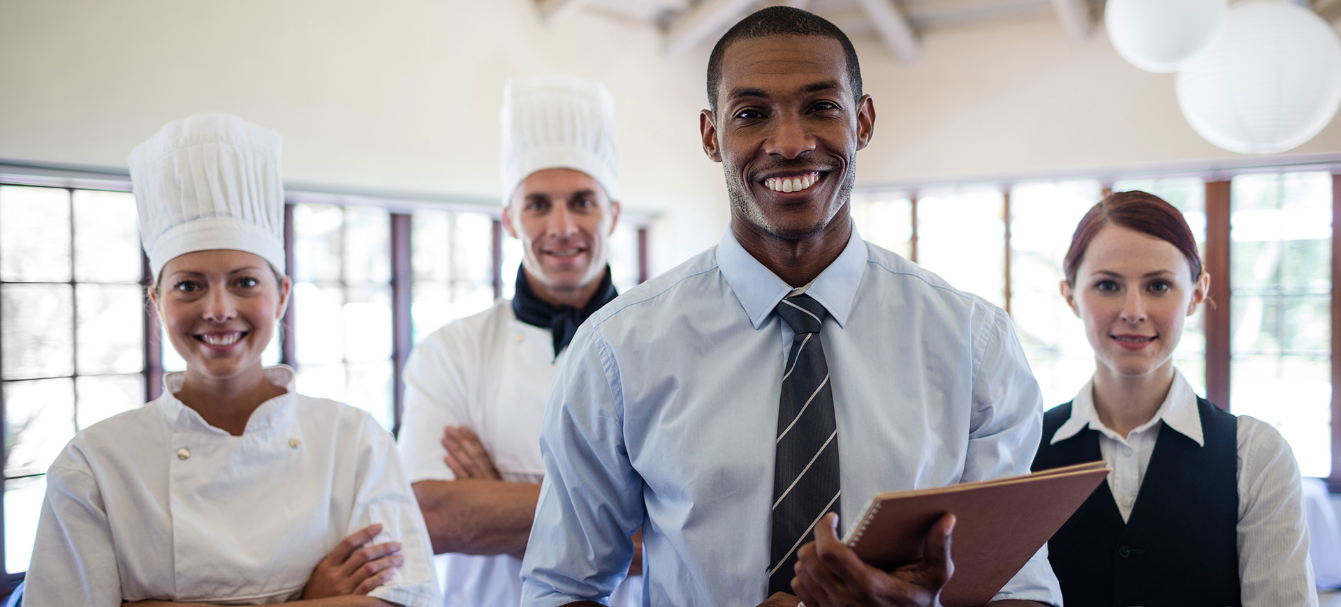 Image of four kitchen workers looking at the camera and smiling